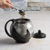 Half Moon Glass Teapot adding tea on counter